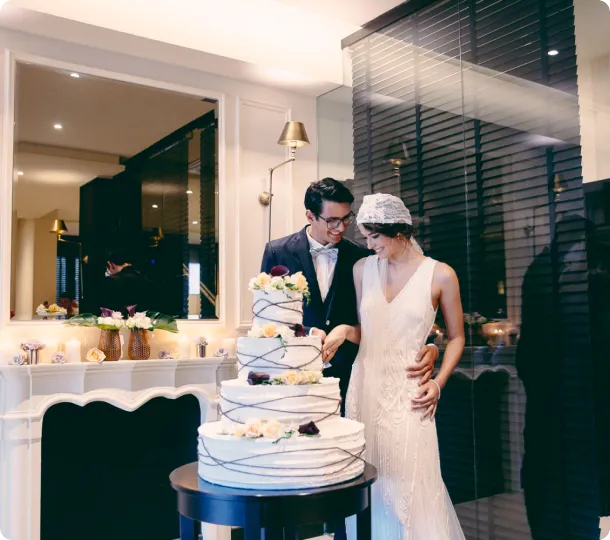 Coppia di sposi che taglia una torta nuziale a tre piani.