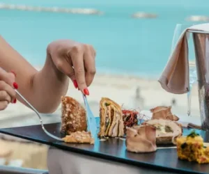 Eine Person genießt eine Auswahl an Gourmet-Speisen am Meer.